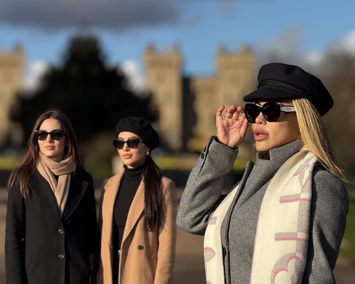 Cris Galera com duas convidadas, de casaco e óculos escuros, numa cidade europeia no inverno